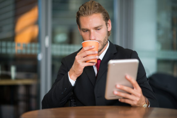 Empresario tomando café mientras revisa correo