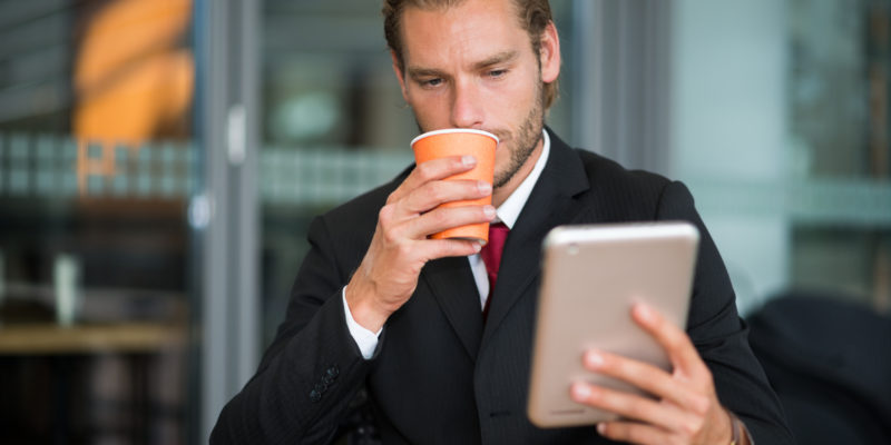 Empresario tomando café mientras revisa correo